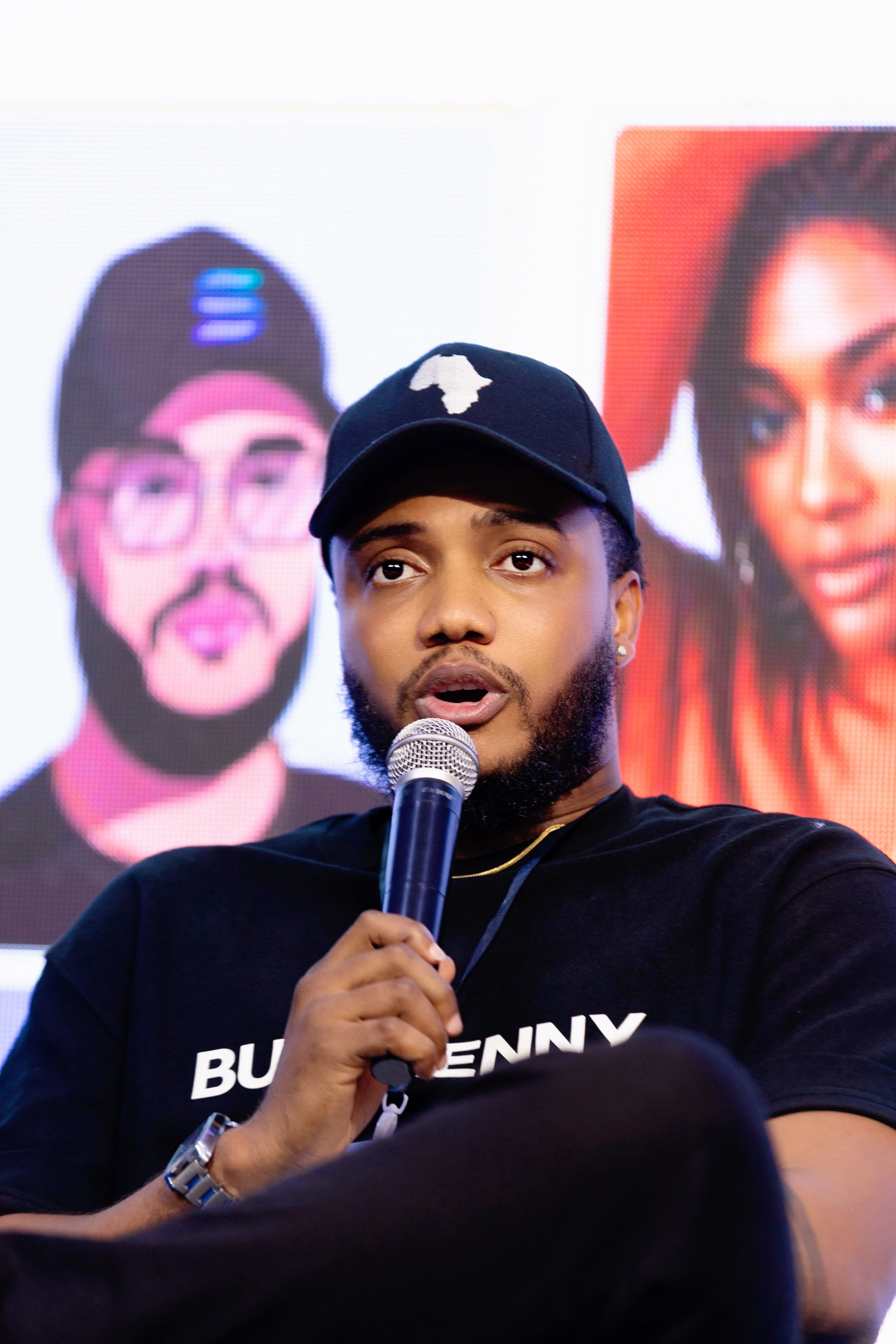 Harrison speaking at panel with microphone wearing BURN ENVY shirt